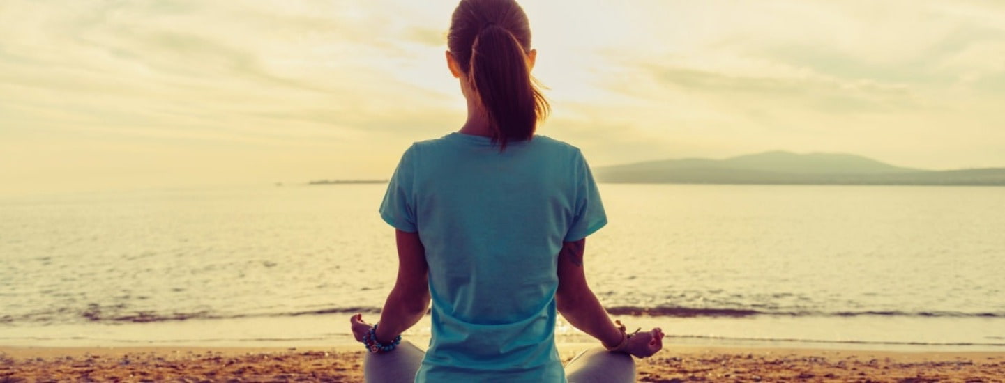 Person sitting on beach experiencing mindful meditation