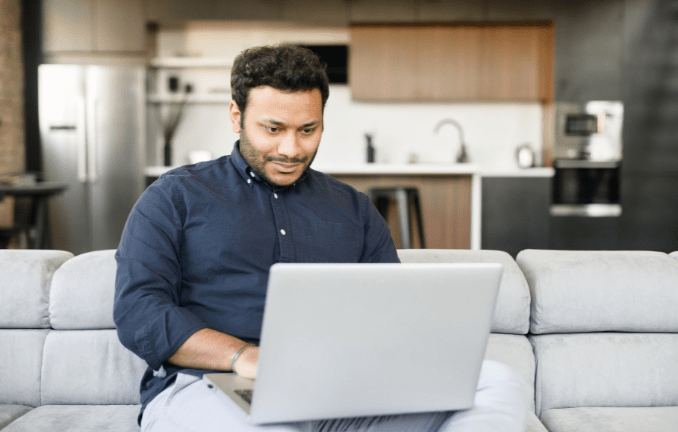 Recruitment marketer sat on sofa review package options on laptop screen