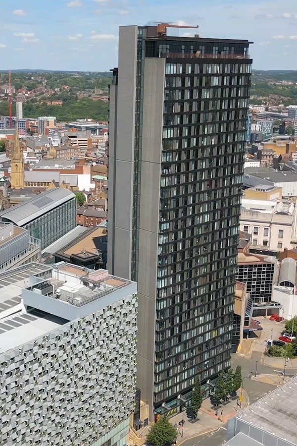 Woman at work desk wearing a white work shirt, with a pen in hand raised up to chin discussing work. 