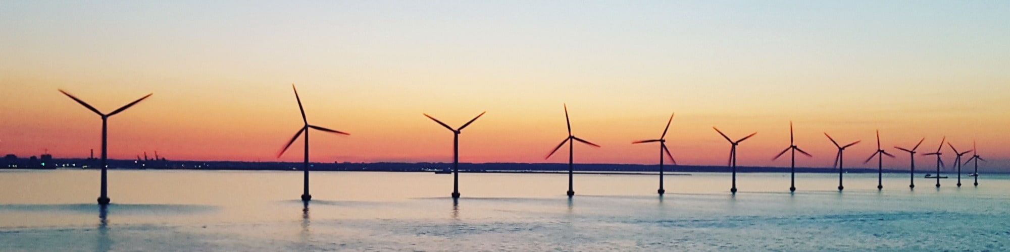 Offshore Wind turbine farm at sunset out at sea at sunset