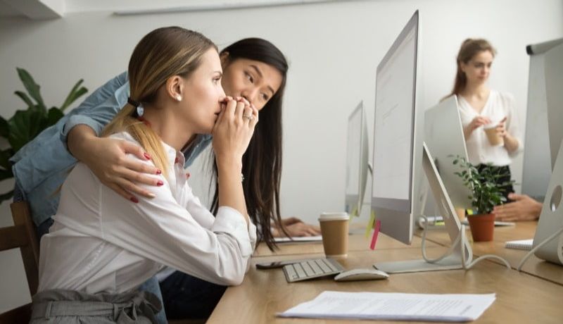 Woman consoling another at her desk