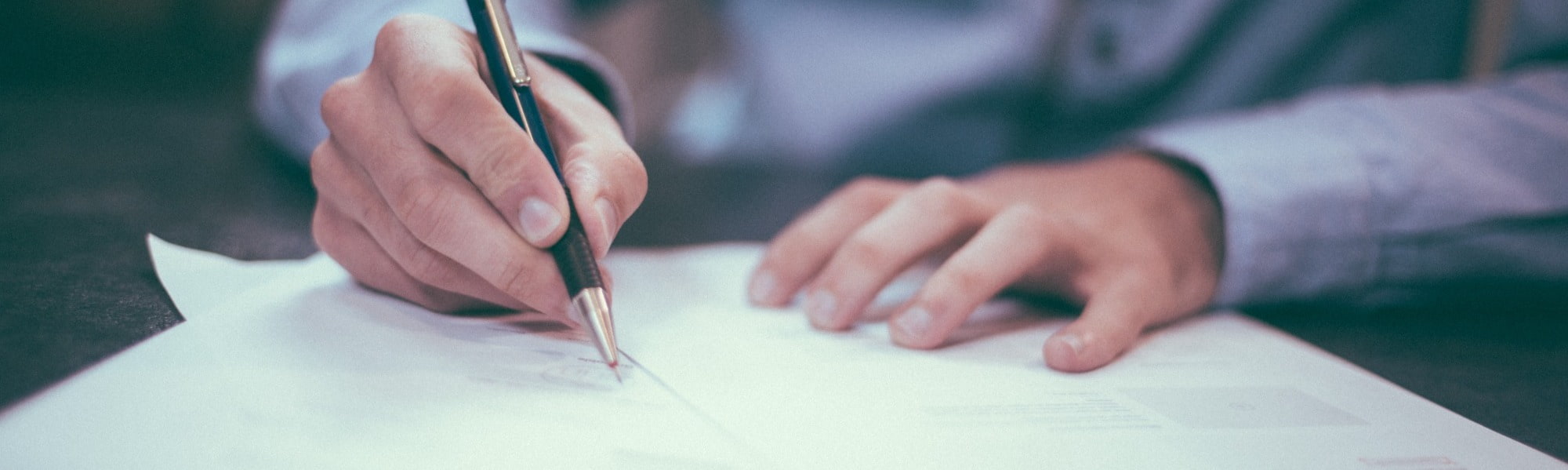 A close up view of a person writing on a piece of paper with a pen